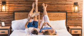 couple-lying-cozy-bed-with-their-legs-up-wall 1